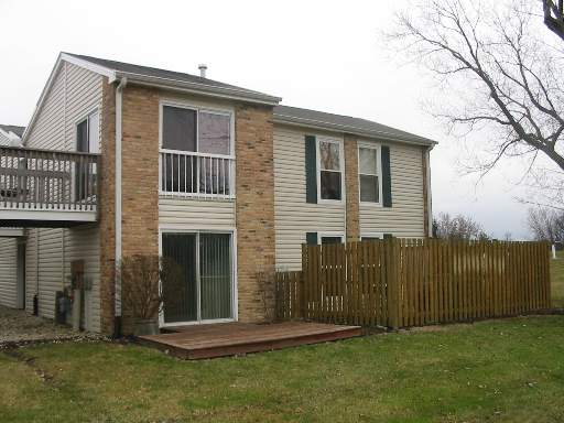 Rear view of a two-story house with sliding glass doors and a fenced wooden deck.
