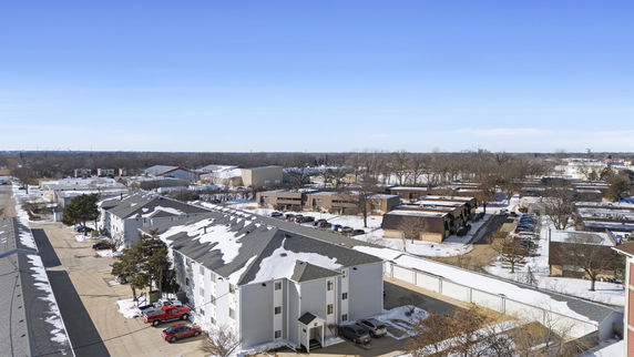 Aerial view of snow-covered residential and commercial buildings in a suburban area.