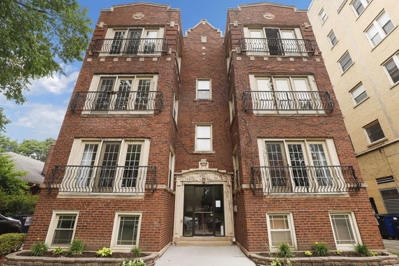 Front view of a multi-story brick apartment building with balconies.