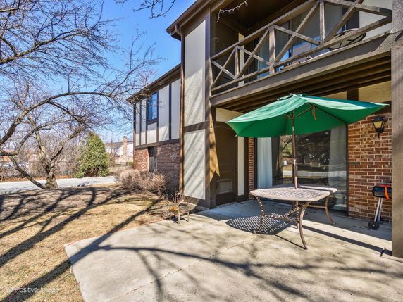 Front view of a house with a balcony and outdoor patio area.