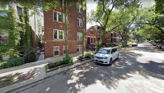 Front view of a multi-story brick building with trees lining the street.