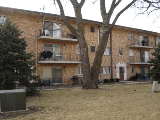 Front view of a three-story brick apartment building with balconies.
