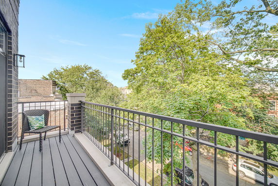 Balcony view overlooking a street with trees and parked cars.