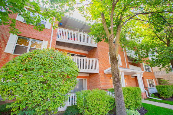 Front view of a multi-story brick apartment building with balconies.