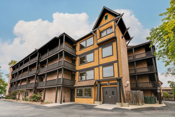 Front view of a four-story residential building with wooden exterior and balconies.