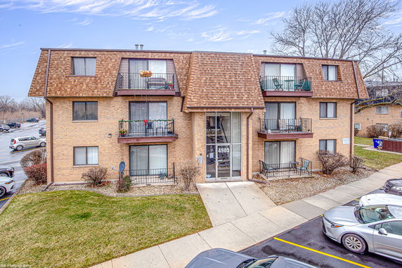 Front view of a three-story apartment building with balconies and a brown roof.