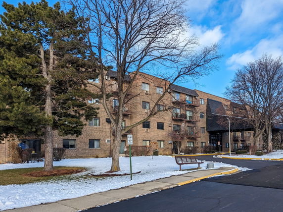 Front view of a multi-story brick apartment building with balconies and an entrance.