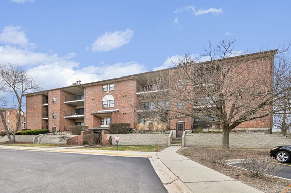 Front view of a multi-story brick apartment building with balconies.