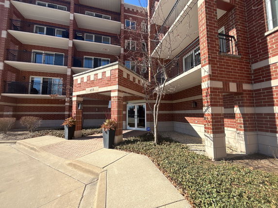 Front view of a multi-story brick building with balconies and main entrance.