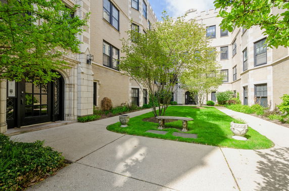 Front view of a multi-story brick building with a landscaped courtyard.