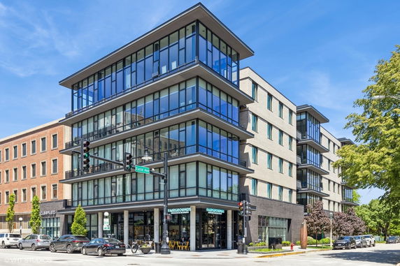 Front view of a modern multi-story building with glass windows and brick facade.