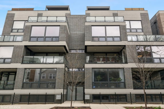 Front view of a modern multi-story building with large windows and balconies.