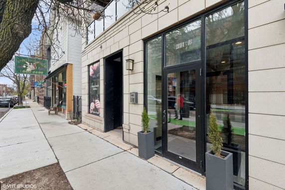 Front view of a storefront with large glass doors and pavement leading up to the entrance.