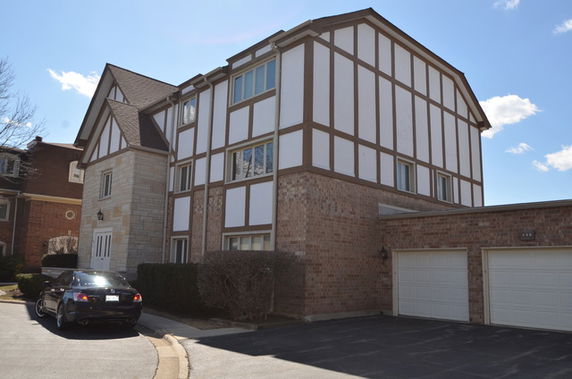 Front view of a multi-story house with Tudor-style architecture and attached garage.