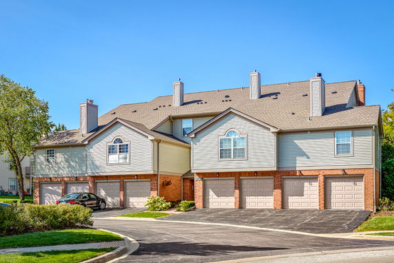 Front view of a townhouse complex with multiple garages and chimneys.