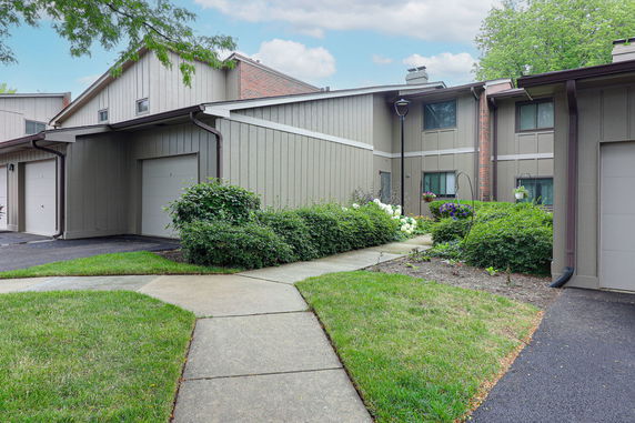 Front view of townhouse units with garages and landscaped pathways.