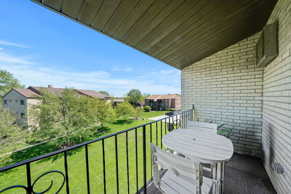 View from a balcony overlooking a grassy area with multiple residential buildings.