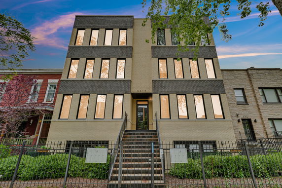 Front view of a three-story building with multiple windows and a central staircase.