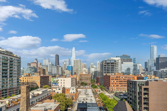 Panoramic view of a city skyline with various skyscrapers under a blue sky.