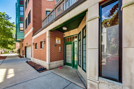 Front view of a brick building with a green door and windows.