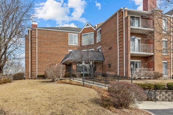 Front view of a multi-story brick apartment building with balconies.