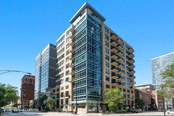 Front view of a multi-story modern apartment building with balconies and large windows.