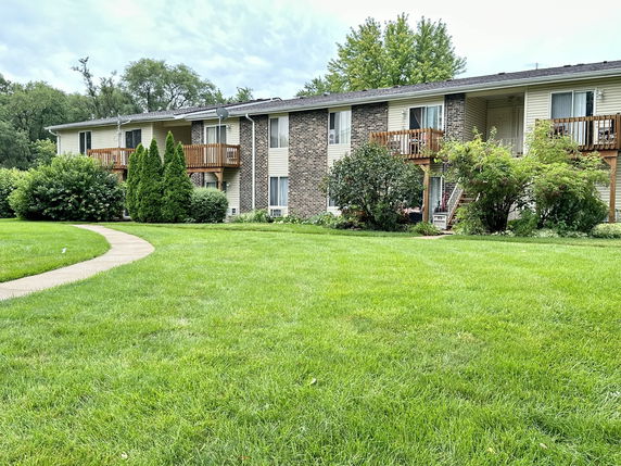 Front view of a two-story building with wooden balconies and a well-maintained lawn.