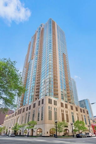 Front view of a tall high-rise building with extensive glass windows and beige exterior.
