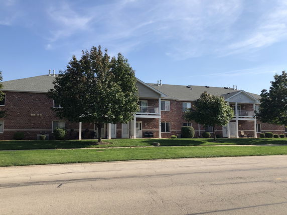 Front view of a two-story brick apartment building with balconies.
