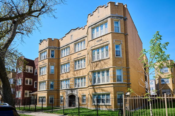 Front view of a three-story brick apartment building with multiple windows.