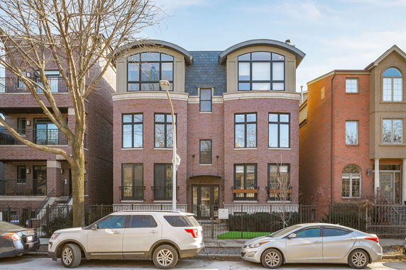 Front view of a multi-story brick building with large windows and arched roofs.