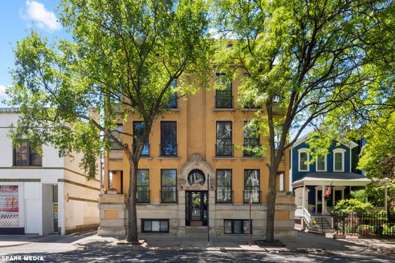 Front view of a three-story residential building with large windows and decorative entrance detailing.