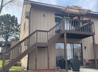 Front view of a two-story house with an external staircase and balcony.