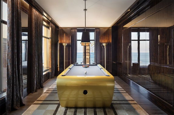 Room with a modern pool table and large windows showing an ocean view.