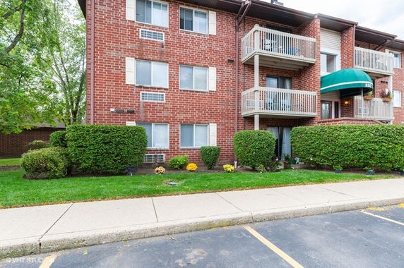 Front view of a three-story brick apartment building with balconies.