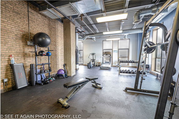 Indoor gym area with exercise equipment and weights.