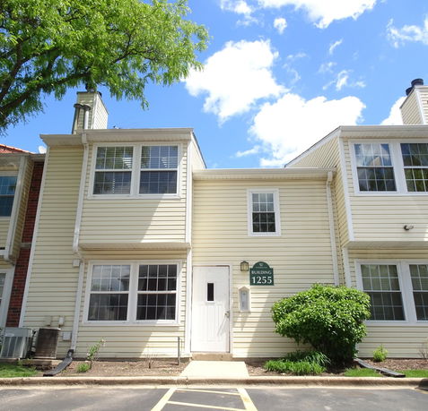 Front view of a multi-story building with white siding and large windows.