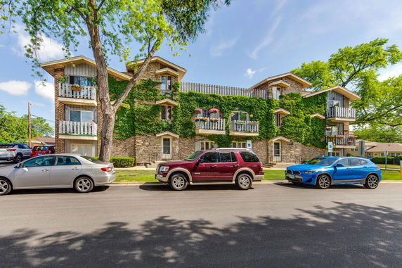 Front view of a multi-story residential building with ivy-covered walls and multiple balconies.