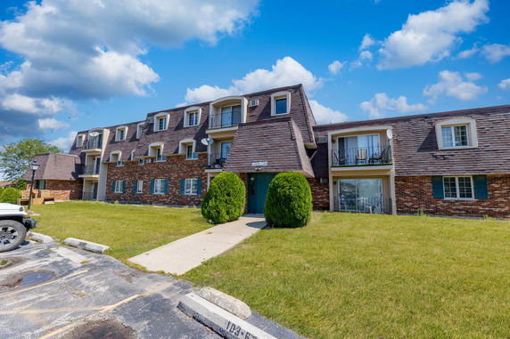Front view of a multi-story residential building with brick facade and balconies.
