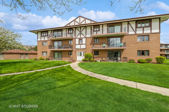 Front view of a multi-story brick apartment building with balconies.