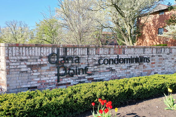 Front view of a brick wall with 'dana point condominiums' signage.