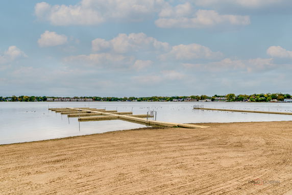 Panoramic view of a sandy beach with wooden docks extending into a calm body of water.