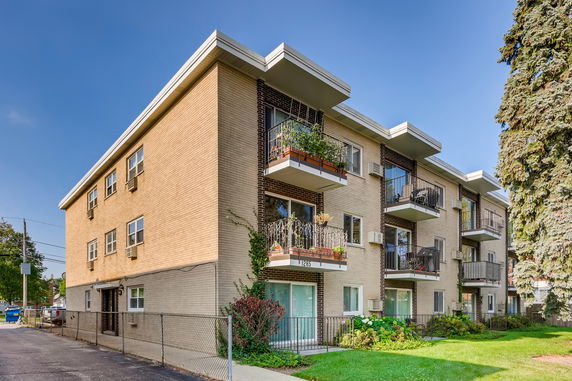 Front view of a multi-story apartment building with several balconies and a flat roof.
