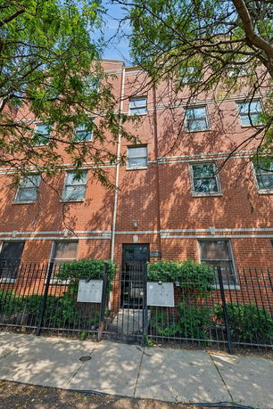 Front view of a multi-story brick residential building with a gated entrance.