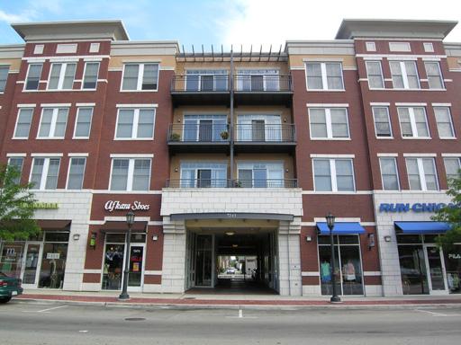 Front view of a multi-story building with brick facade and street-level shops.