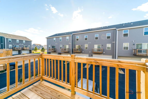 View from a wooden balcony overlooking multiple townhouses with garages.