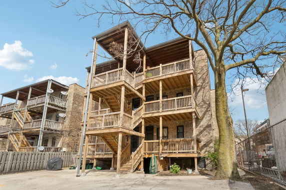 Rear view of a multi-story building with wooden balconies and staircases.