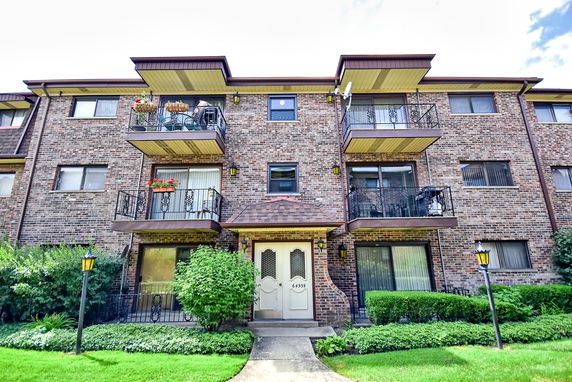Front view of a three-story brick apartment building with balconies.