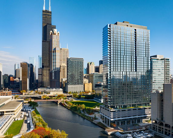 Front view of a high-rise building with glass facade next to a river.