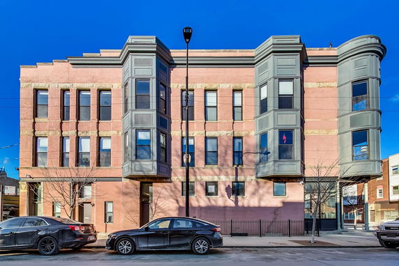 Front view of a three-story building with large bay windows and brick exterior.